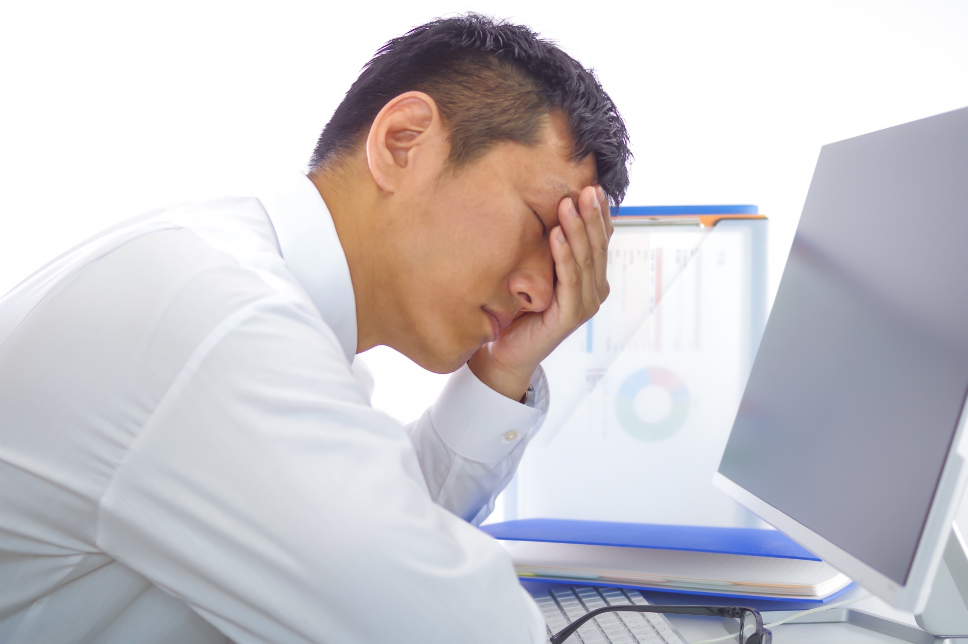 パソコン画面を見て頭を抱える男性